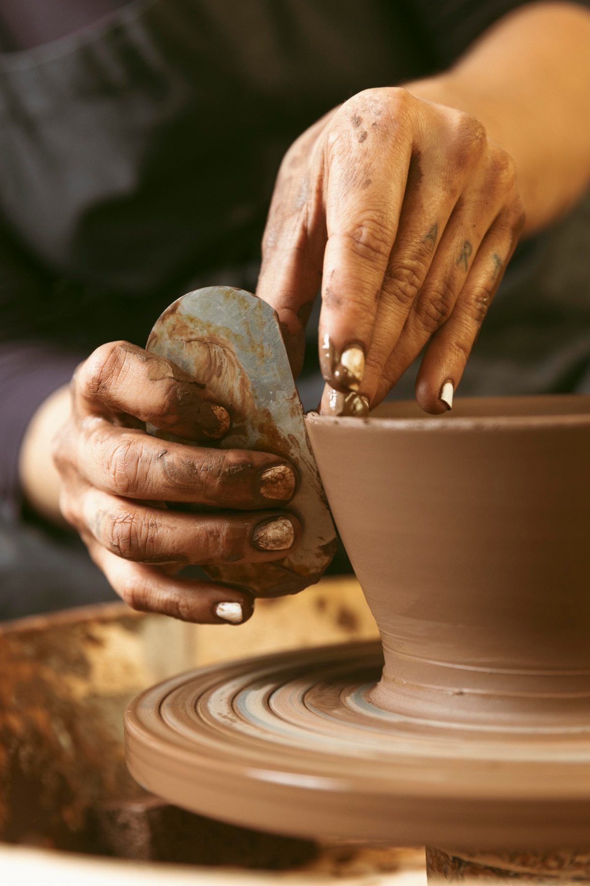 A potter shaping a clay vessel on the wheel